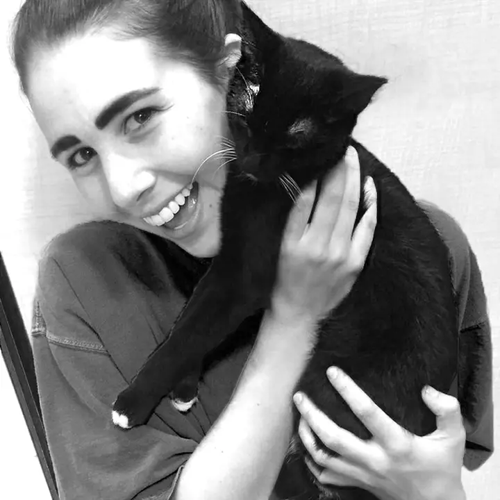 black and white image of a woman holding a black cat up to her face